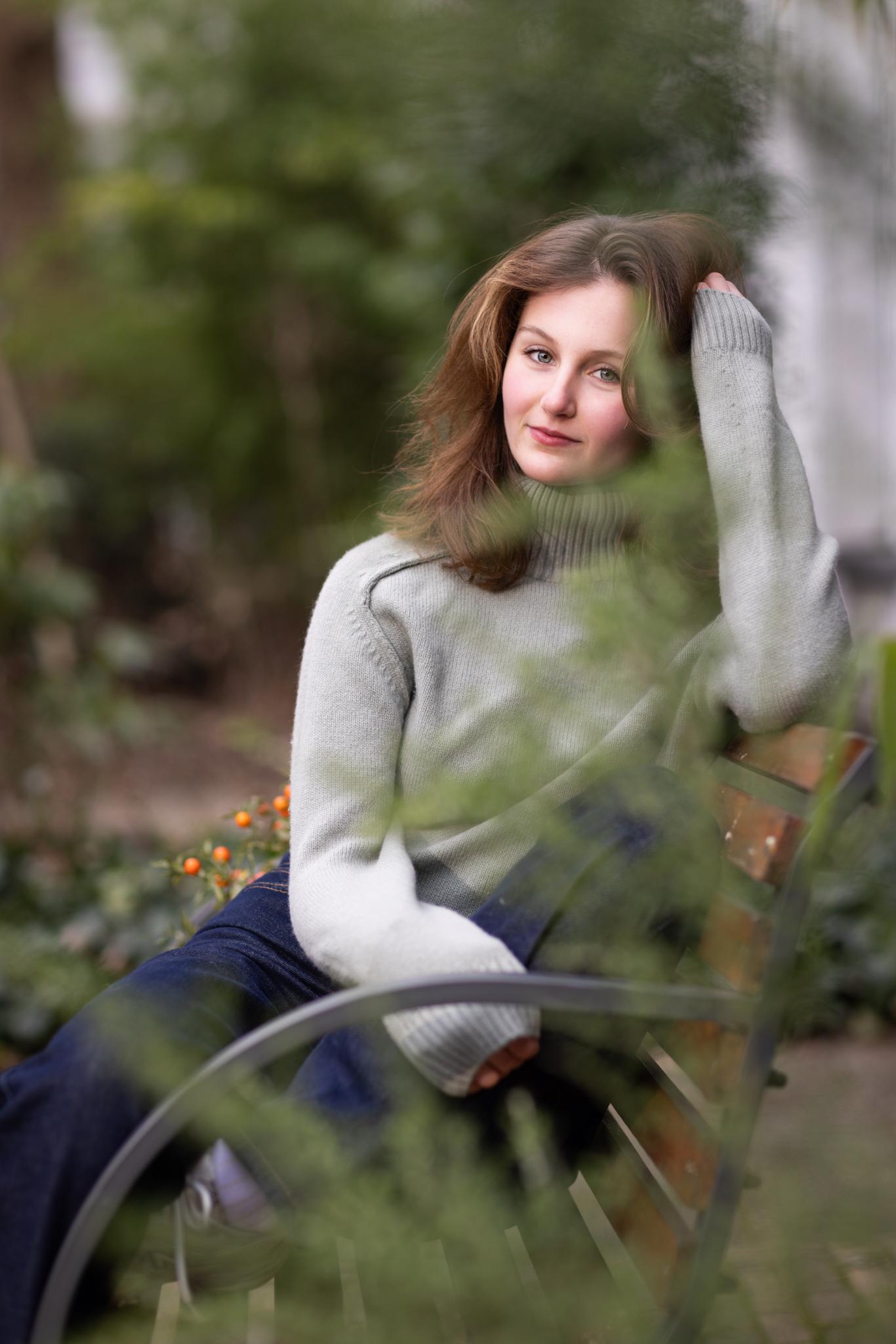 Portret van jonge vrouw achter zachte begroeiing, dromerig buitenportret.