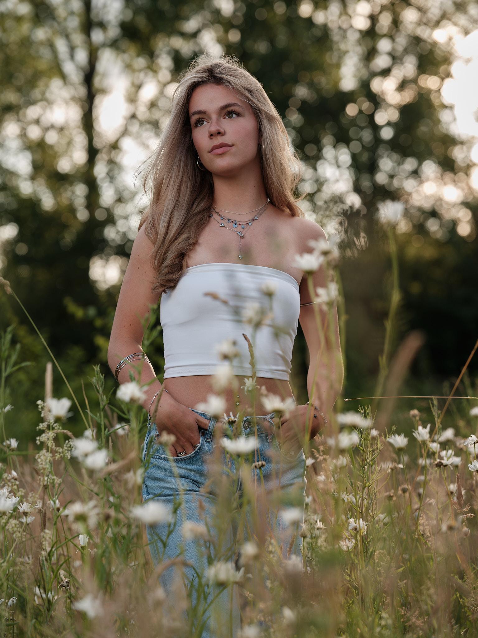 Model in bloemenveld met witte top