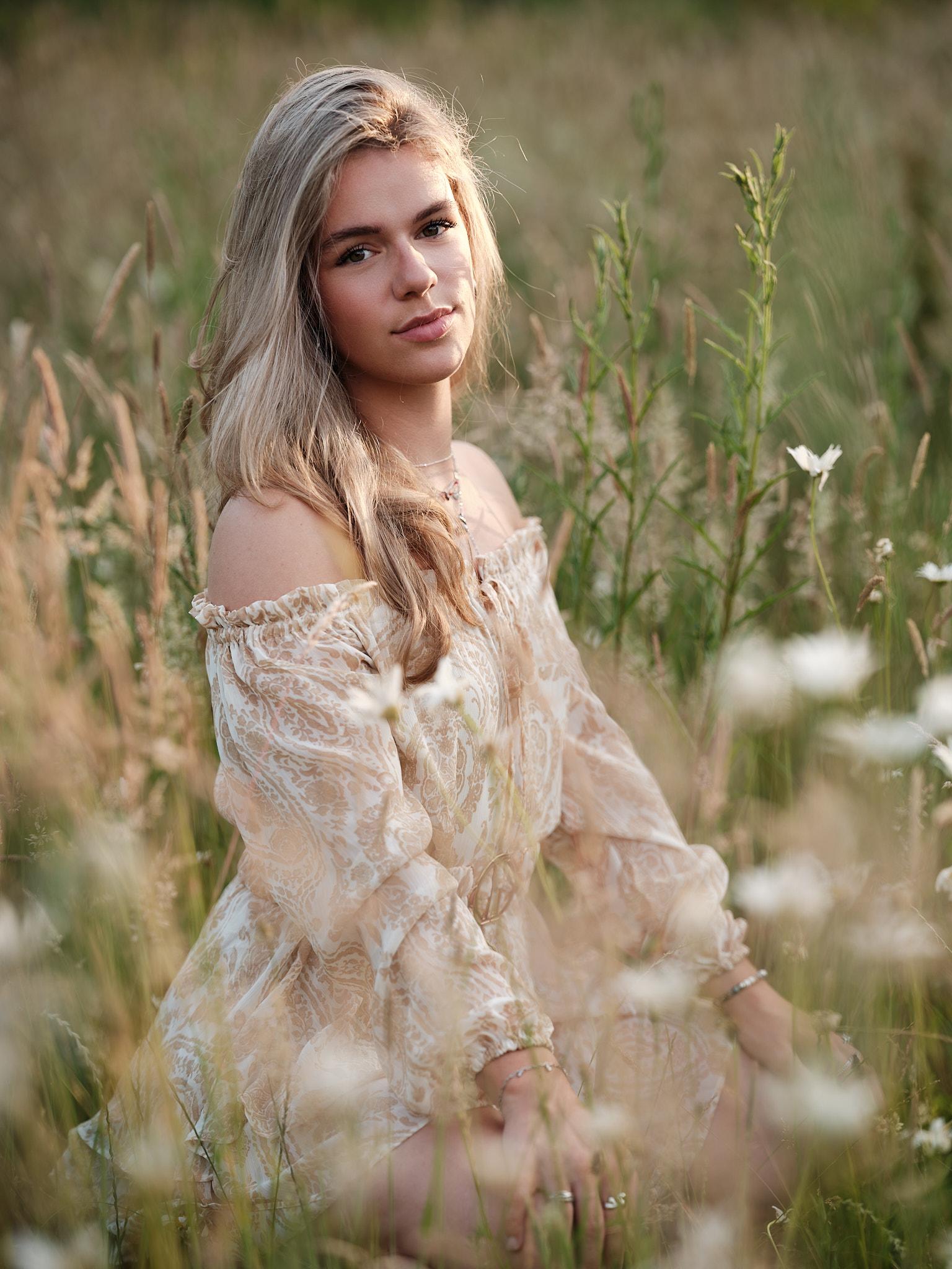 Model zittend in veld met zachte blik