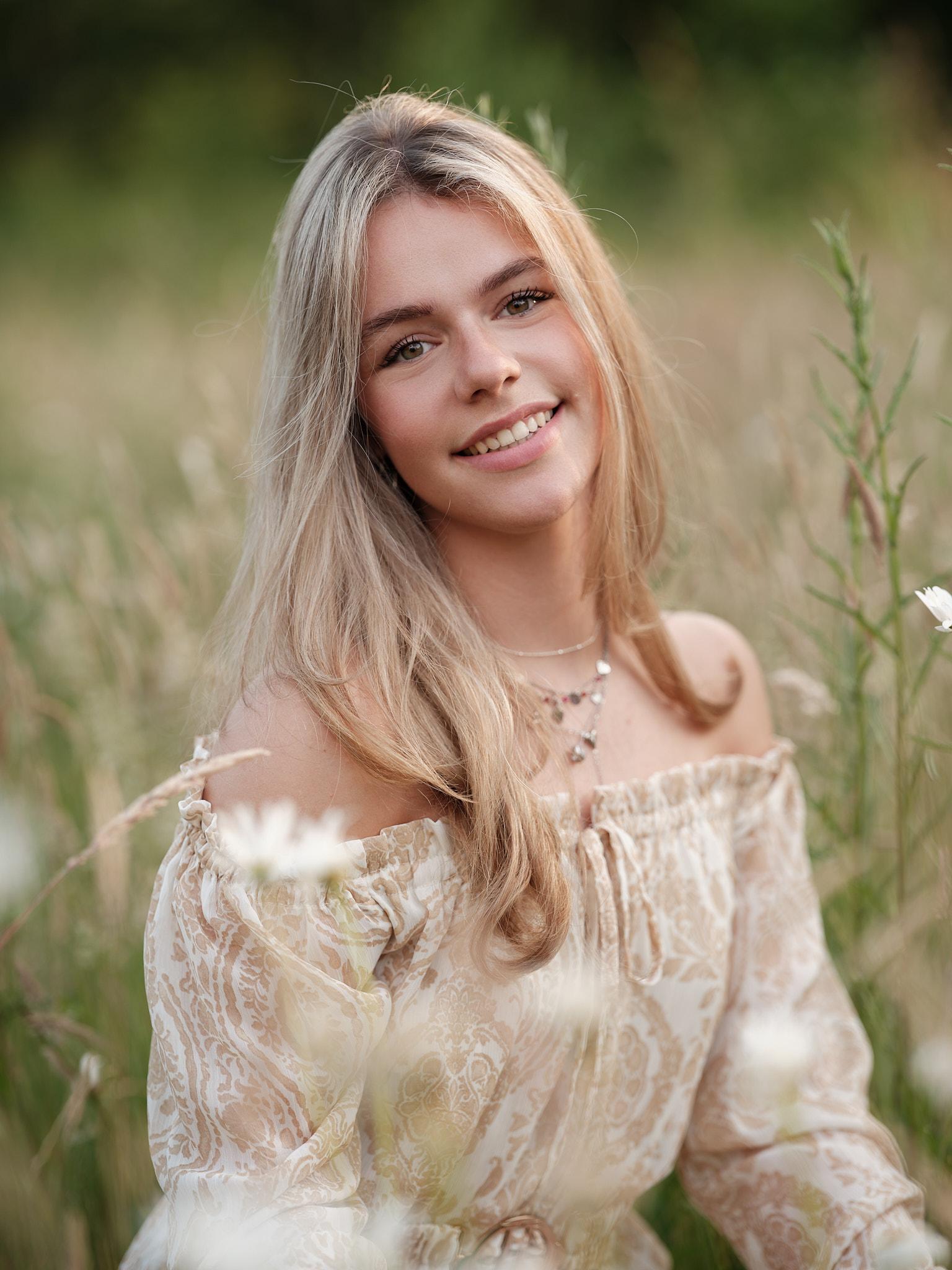 Model zittend in veld met lichte jurk